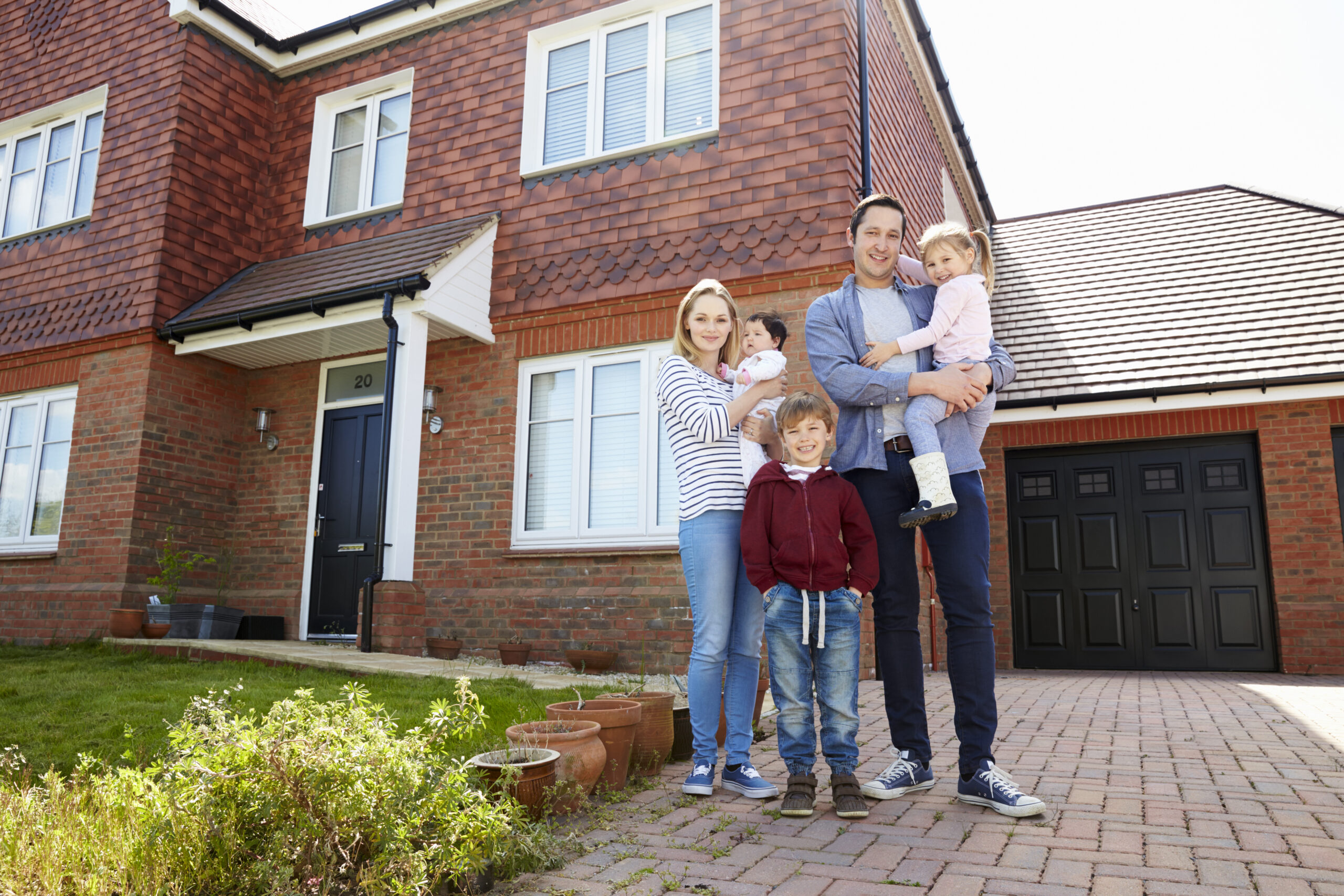 Portrait Of Young Family Standing Outside New Home